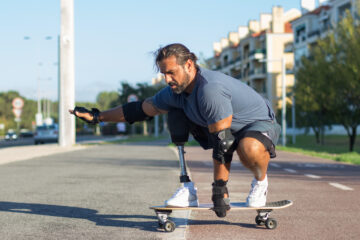 Attractive person with disability doing sports in park. Mid adult sportsman skateboarding down special road in concentration. Sport, disability, training concept